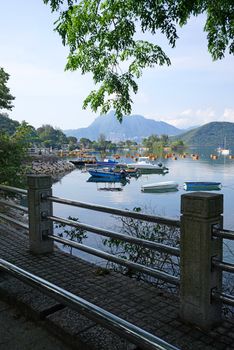 The vertical yacht, fishing and recreational boats on lake, fence and mountains