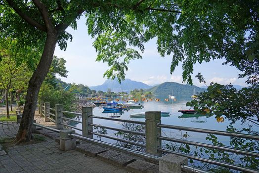 The yacht, fishing and recreational boats on lake, park fence and mountains