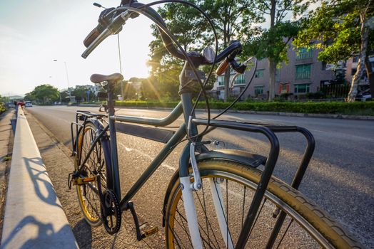 The green retro bicycle with brown leather seat and flare light from sun