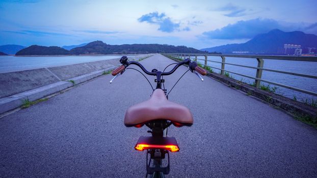 The rear of retro bicycle with brown leather seat and handle from perspective angle