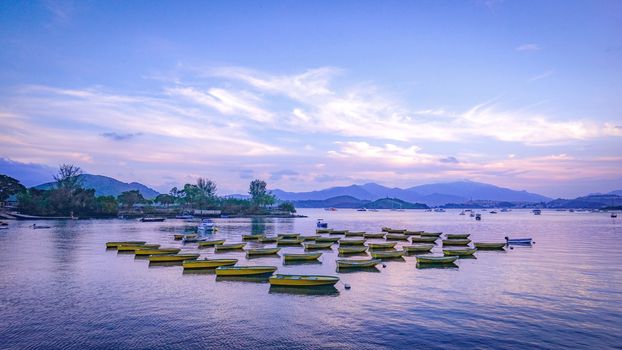 The recreational and fishing boats are parked on the lake at sunset
