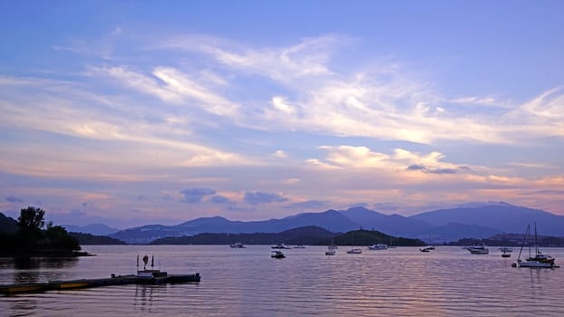 Pier, yacht, sailboats, mountains, clouds and beautiful gradent sky at sunset