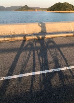 The vertical shadow of bicycle in the street with mountains and lake