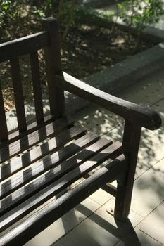 Garden dark brwon wooden bench with the day light and shadow