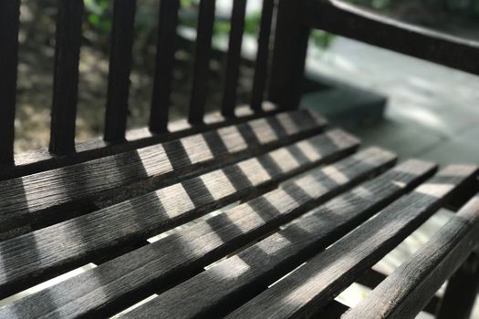 Garden dark brwon wooden bench with the day light and shadow