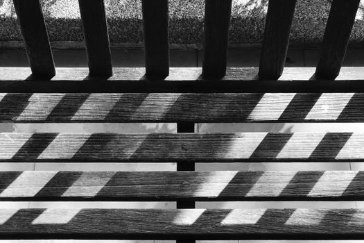 Black and white garden wooden bench with the day light and shadow