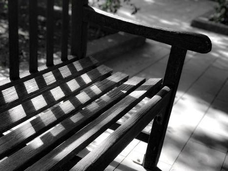 Black and white garden wooden bench with the day light and shadow