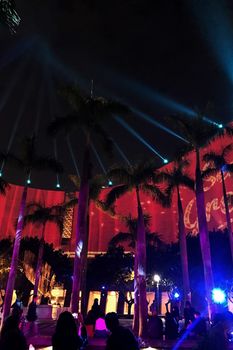 Colorful laser show performance around the architectural building in the city at night time