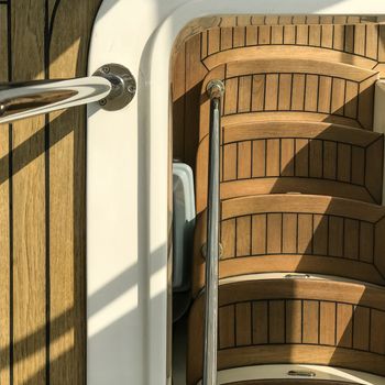 wooden staircase in the white yacht with the sunlight and shadow