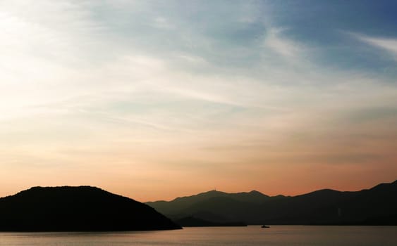 The silhouette of boat and mountain with the gradient sunset
