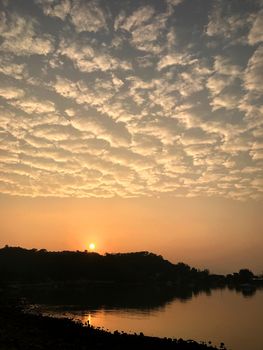 High cumulus cloud, orange sky, lake and the sun at sunset