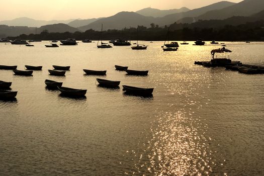 The silhouette of fishing boat and pier on lake with mountain at sunset