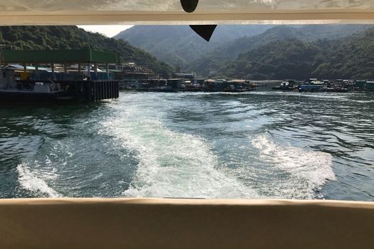 The back view of the white motor yacht leaving from the pier