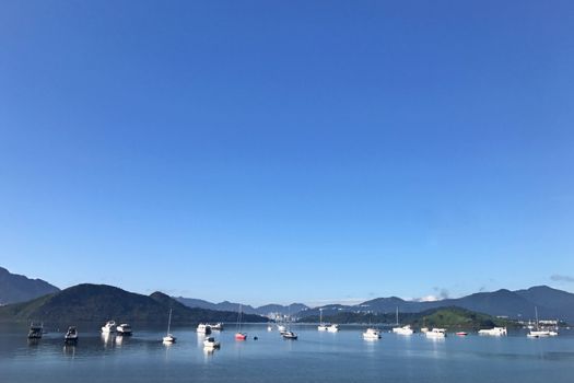 Mountain, blue sky, boats, yacht and sailboats on the lake