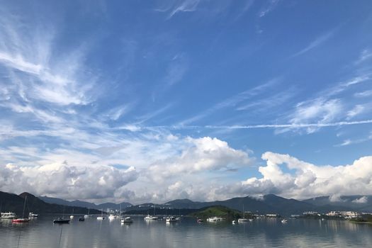 The mountain, blue sky, boats, yacht and sailboats on the lake