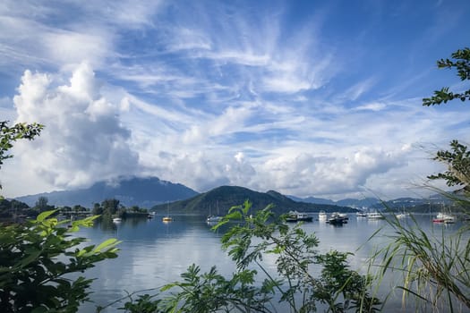 Green plants, mountain, blue sky, boats, yacht and sailboats on the lake