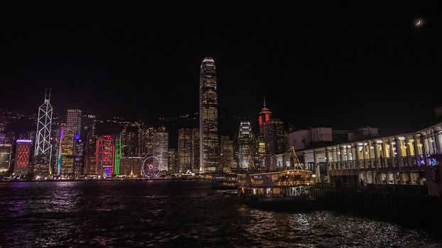 Hong Kong cityscape, building and ferry boat near victoria river in the evening