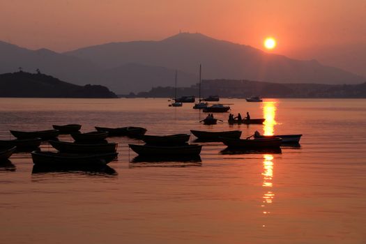 The silhouette of recreational boat, mountain with reflection at sunset