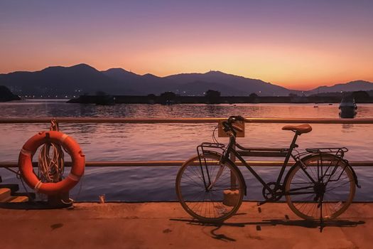 The retro bicycle, red lifebelt, pier at gradient sky