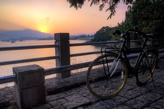 The silhouette of bicycle, fence and ocean at sunset