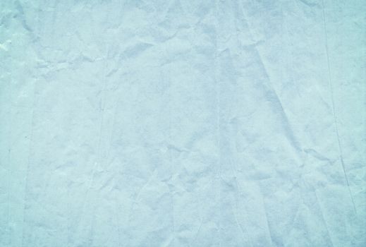 The light blue blank crumpled and grungy textured paper background