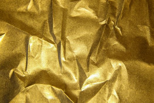 The golden shiny abstract metallic crumpled paper background
