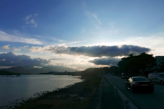 Ocean, dramatic sky and cars on the road