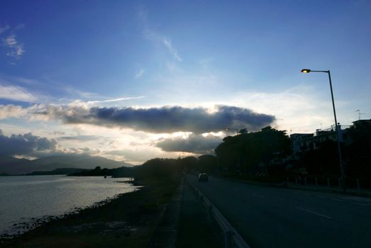 Ocean, dramatic sky and the car on road