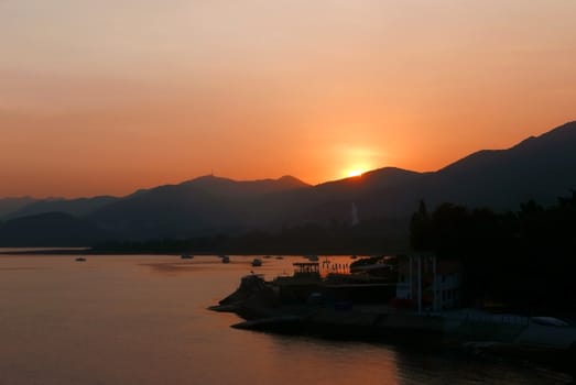 The silhouette of boats, sun, mountain and sea at sunset