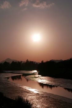 The silhouette of tree, mountain and river with reflection at sunset