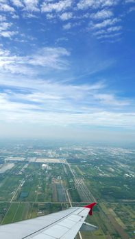 Vertical wing of airplane with green land and blue sky