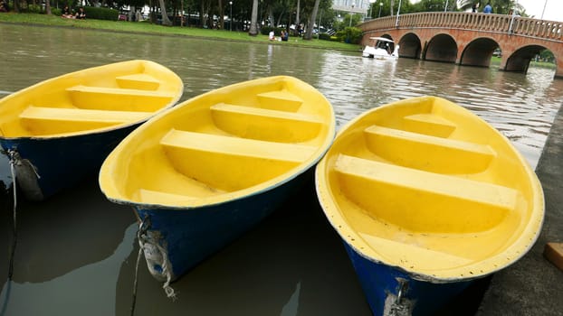 Old blue and yellow recreation boat and the bridge on the lake 