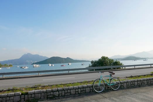 Mint green retro parked bicycle near the lake and road