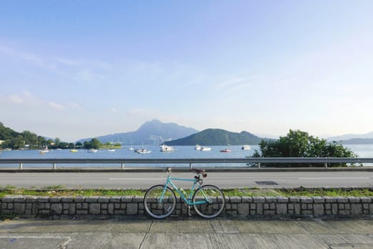 Mint green retro parked bicycle near the lake and road