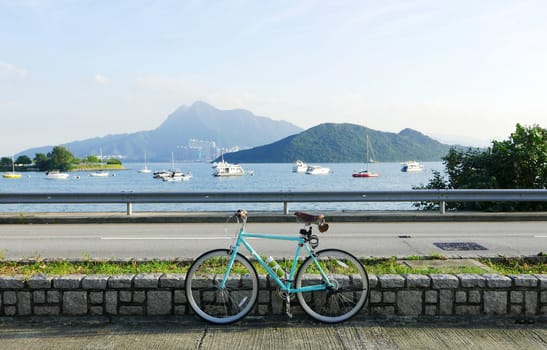 Mint green retro parked bicycle near the lake and road