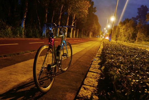 Classic parked bicycle near the road at night