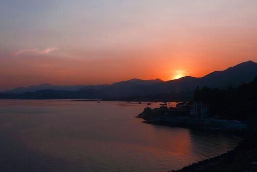 The silhouette of mountain, boats and lake at sunset