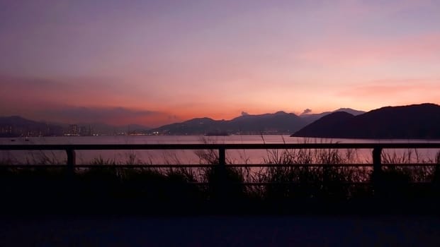 The silhouette of mountain, plant, fence, residential building and ocean before evening