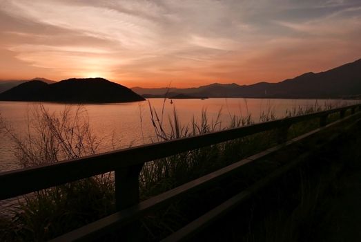 The silhouette of mountain, plant, fence cloud and gradient orange sky