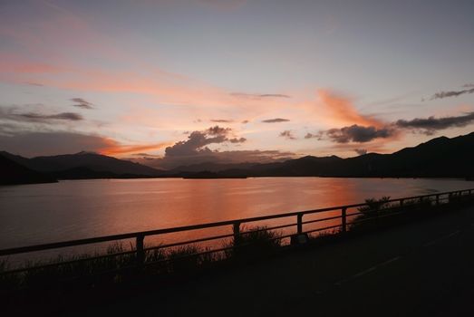 The silhouette of mountain, plant, fence, gradient sky and ocean at sunset