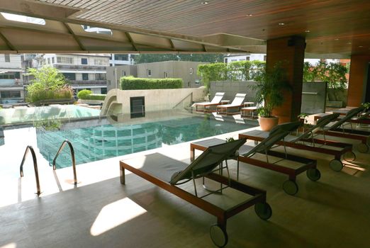 The swimming with reflection of the city and suntan chair