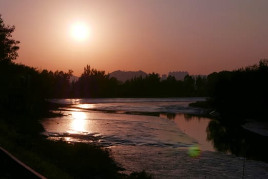 The silhouette of tree, mountain and river with reflection at sunset