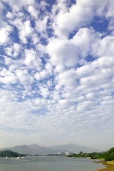 Blue sky, white cloudscape, ocean and the mountain