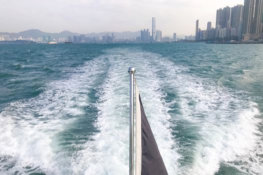 The end of white yacht with flag, Hong Kong building and victoria river