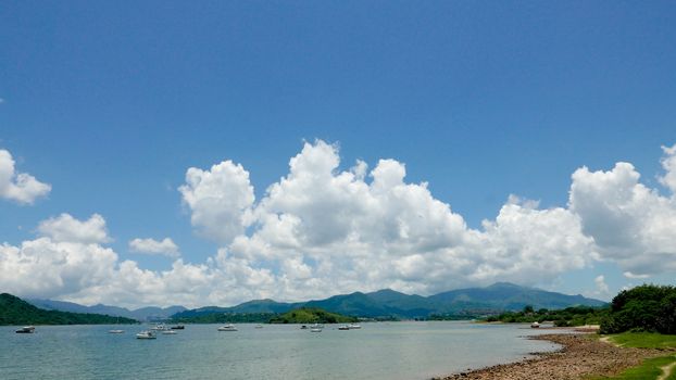 Green mountain, lake, boat, blue sky and the white cloud