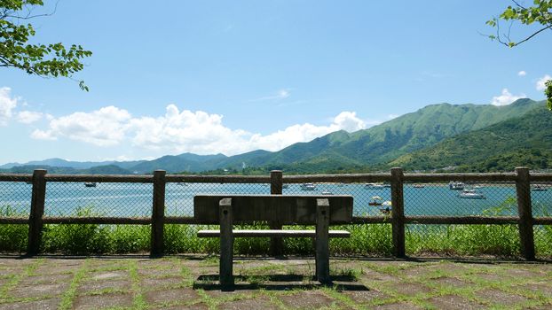 Outdoor wooden fence, bench, mountain and the motorboats