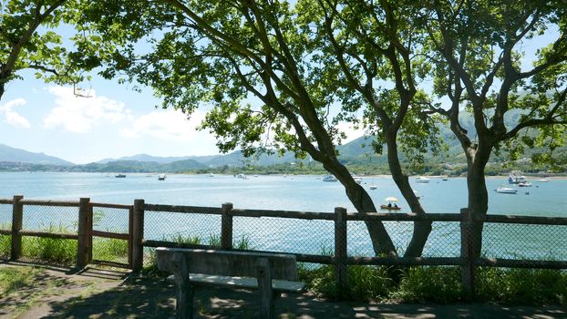 Outdoor bench, trees, mountain and the fishing boats