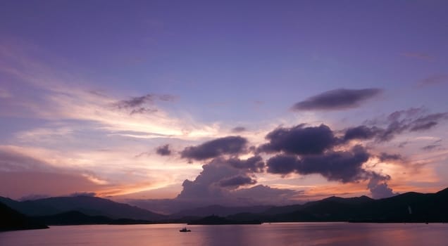 mountain, dramatic sky, boat on the sea at sunset