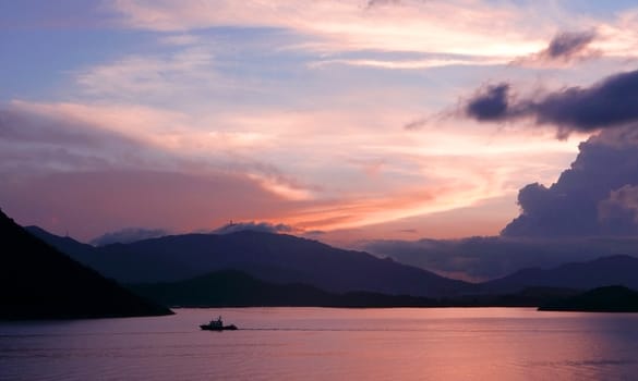 mountain, dramatic sky, boat on the sea at sunset