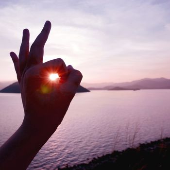 The sunlight is from human hand with mountain and the sea